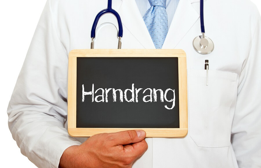 Oberkörper eines Arztes mit Tafel mit der Aufschrift Harndrang in den Händen