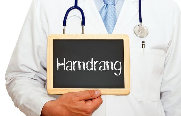 Arzt mit Schild "Harndrang" in den Händen